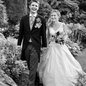 The happy newlyweds take a stroll through the wonderful flower borders at their Hertfordshire wedding reception venue Chenies Manor