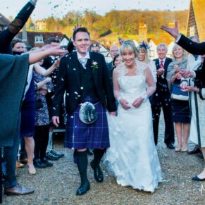 The newlyweds make their way through the colourful confetti aisle at their Kings Chapel wedding in Old Amersham
