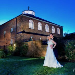 Night shot of the bride and groom under dusky blue skies outside the Kings Chapel in Old Amersham