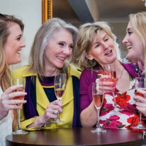 Candid moment between four ladies captured during the drinks reception indoors at the Kings Chapel in Old Amersham