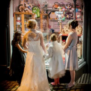 The ladies glance into a window after stepping into the high street for some photo opportunities during this Kings Chapel wedding in Old Amersham