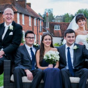 Relaxed family group pose with some historic old town buildings behind them at this Kings Chapel in Old Amersham wedding