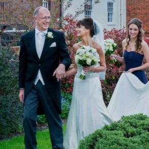 The newlyweds walking through the grounds with their bridesmaids at their Kings Chapel wedding in Old Amersham