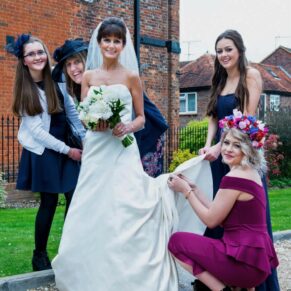 The ladies assist the bride with her gown in the grounds of the Kings Chapel in Old Amersham