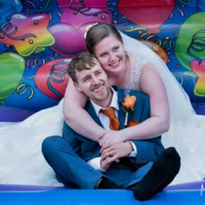 Buckinghamshire Marquee Wedding Photography - bouncy castle backdrop for this relaxed pose with the bride and groom