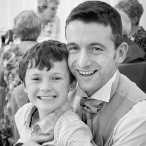 A father and son embrace for a photo during the drinks reception in the venue's gardens