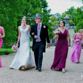 The bridal entourage walk along the gravel driveway towards the parish church in the village
