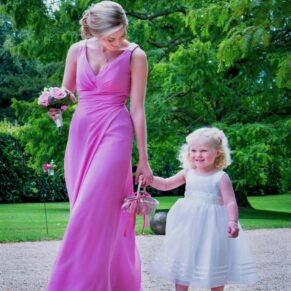 The colourful bridesmaid and flower walk towards the church hand in hand along the quiet lane
