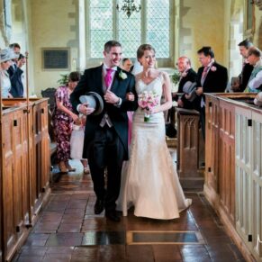 The newlyweds exit the historic parish church as their guests watch on from the pews