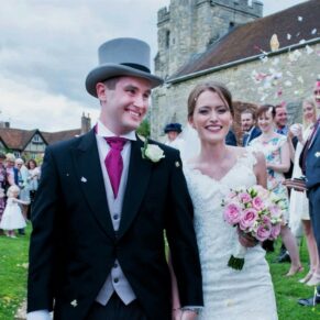 The smiling bride and groom make their way through the colourful confetti aisle as they exit the parish church