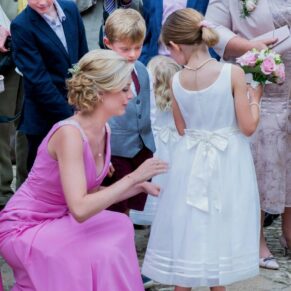 Adjustments being made to the flower girl's dress before she's ready for the photographer's next picture