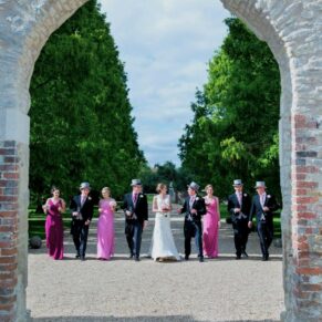 The bridal party captured walking towards the camera through one of the many archways at this historic property