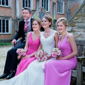 The bride captured in a relaxed pose with her siblings in the courtyard of this Grade I listed property