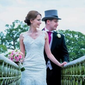The bride and groom cross the bridge as they look up stream towards the venue