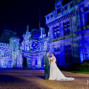 Buckinghamshire Winter Wedding Photography - the newlyweds stood in front of the illuminated Waddesdon Manor