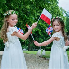 Flower girls waving their flags during the wedding drinks reception in the grounds of Chenies Manor