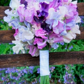 Stunning sweet pea bouquet resting on a bench within the gardens of this historic Hertfordshire wedding venue