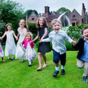 Kids giggling and running through the grounds of Chenies Manor on a glorious summery wedding day