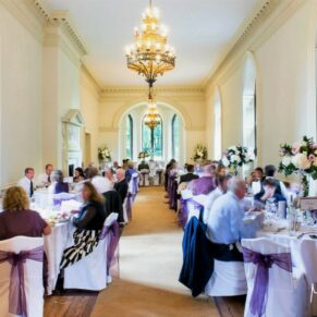 Photography of the stunning dining room with all the wedding guests seated and captured during the wedding breakfast at Clearwell Castle