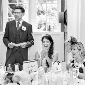 Photography of the groom's wedding speech in progress at Clearwell Castle watched by his appreciative wife and mum at the top table
