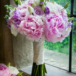 Beautiful pale pink wedding bouquet captured in this stone mullioned feature window at Clearwell Castle