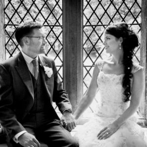 Photography of the bride and groom sat in a huge feature window within the castle on their wedding day at Clearwell Castle