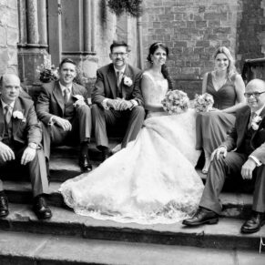 Photography of the wedding bridal party in a relaxed pose on Clearwell Castle's grand entrance steps
