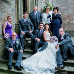The bride and groom and the bridal bridal party strike a relaxed pose on the steps of this wonderful summer celebration at Clearwell Castle