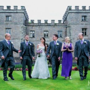 The smiling wedding bridal party stroll towards the camera at this wonderful summer wedding in the Forest of Dean at Clearwell Castle