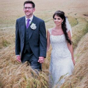 The newlyweds take a stroll through the wheat meadow in the adjacent farmers meadow during their special wedding day at Clearwell Castle