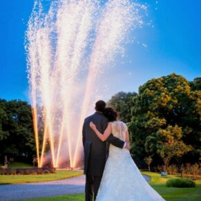 Photography of the newlyweds watching their colourful and dramatic fireworks display in the gardens during their evening wedding reception at Clearwell Castle