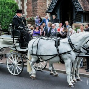 Photography of the carriage as it is preparing to depart from the village church before it makes its way to the wedding drinks reception next door at Clearwell Castle