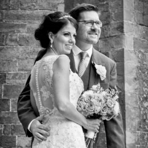 Photography of the newlyweds striking a formal wedding pose in front of Clearwell Castle's main entrance