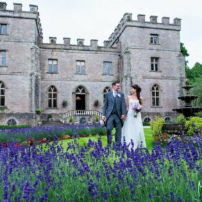 Photography of the newlyweds taking a stroll through the summery lavender borders at the front of Clearwell Castle on their wedding day