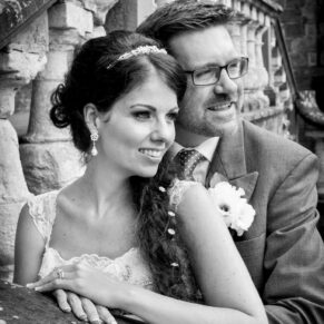 The bride and groom pose for a wedding photo at the main entrance doorway on their wedding day at Clearwell Castle in the Forest of Dean
