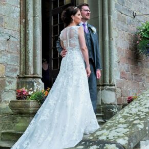 The bride and groom pose for a photo at the main entrance doorway on their special wedding day at Clearwell Castle