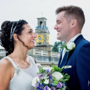 Photography of the newlyweds with the clock tower behind them captured from the roof terrace at their Cliveden House wedding