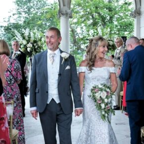 The bride and groom exit the outdoor civil ceremony to lots of smiles from their guests during their Cliveden House summer wedding