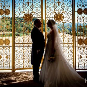 The newlyweds captured in silhouette against the gilded gates to the Sounding Chamber on the South Terrace of Cliveden House on their wedding day