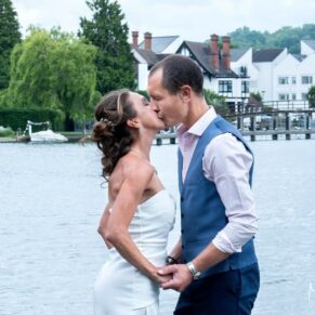 A romantic moment between the newlyweds as they stand beside the River Thames during their Compleat Angler wedding