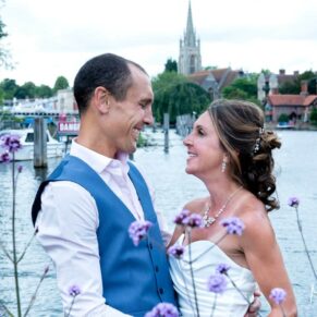 The newlyweds captured by the river with Marlow Church and Bridge off in the distance