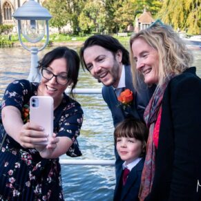 Candid moment taken during the drinks reception of three guests capturing a selfie with a river backdrop