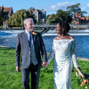 The newlyweds take a stroll beside the weir on the River Thames at their Compleat Angler wedding