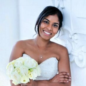 The bride strikes a smiley pose beside Danesfield House's stone emblem under the main entrance arch on her wedding daye Danesfield House's stone emblem under the main entrance arch