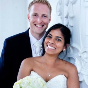 The newlyweds pose for a close-up portrait beside Danesfield House Hotel's stone emblem in the entrance arch on wedding day