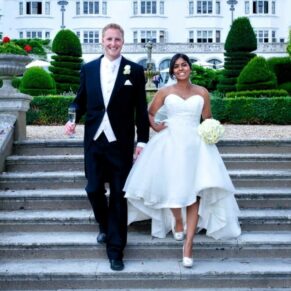 The smiling newlyweds walk down the main garden steps at their Danesfield House Hotel wedding