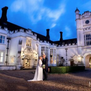 Floodlit pose of the newlyweds under dusky blue skies in the main courtyard of the fabulous Danesfield House Hotel in Buckinghamshire