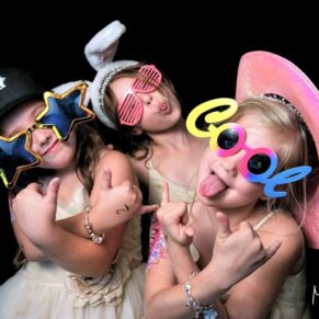 Three flower girls strike a crazy pose in the photo-booth during this evening wedding reception at Danesfield House Hotel
