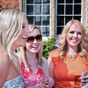 Candid capture taken during the outdoor drinks reception of three ladies giggling