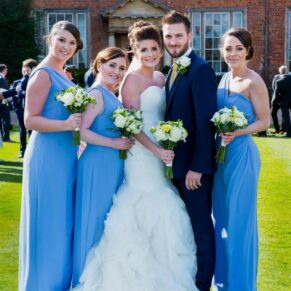 The bride and groom with their bridesmaids in front of the venue on a glorious summer's day